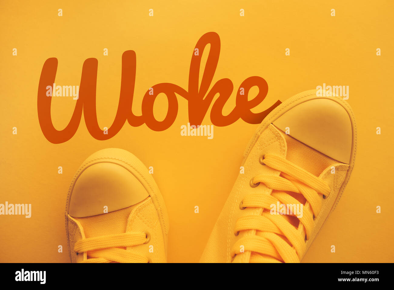 Words and phrases millennials use, conceptual image with young person in yellow sneakers standing directly above text - Woke Stock Photo
