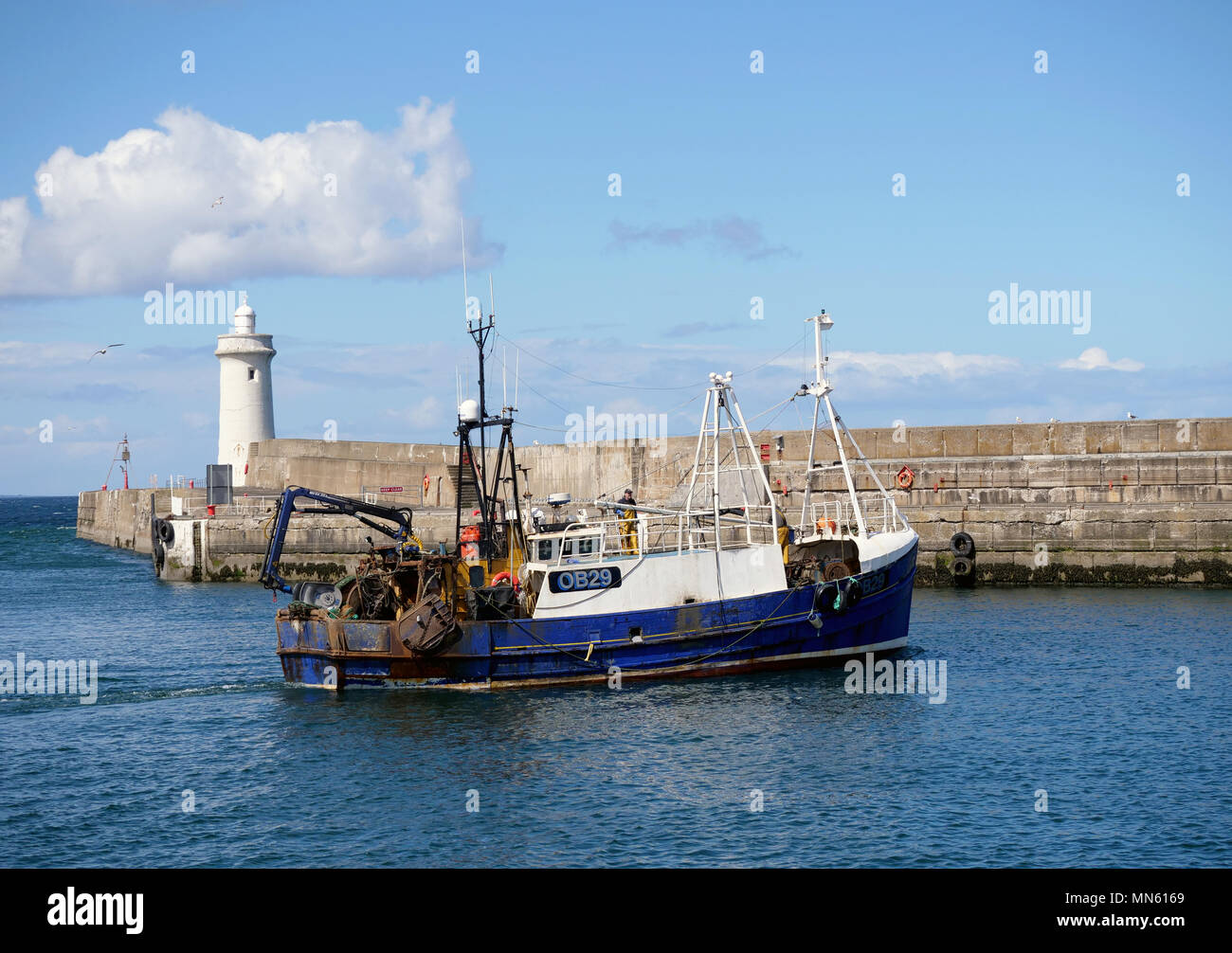 A fishing boat and the Lighthouse in Buckie Harbour, Moray, Scotland Stock Photo