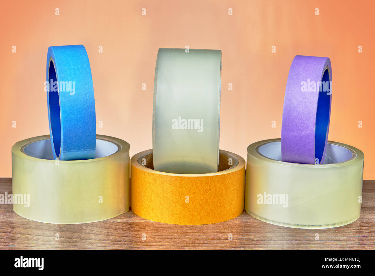 Different types of adhesive tape are lined on an orange background