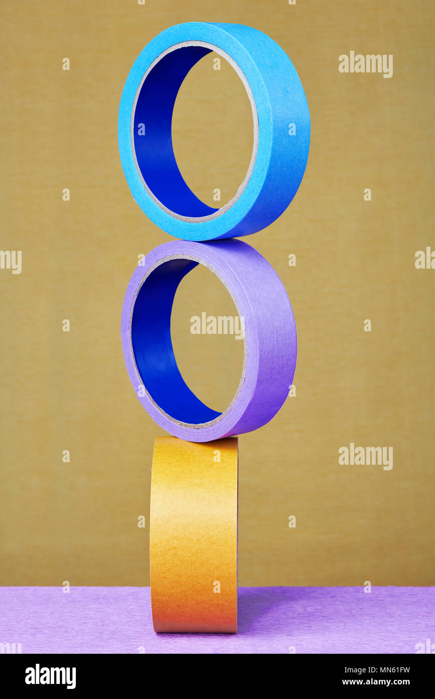 Three rolls of color sticky tape balanced on yellow background Stock