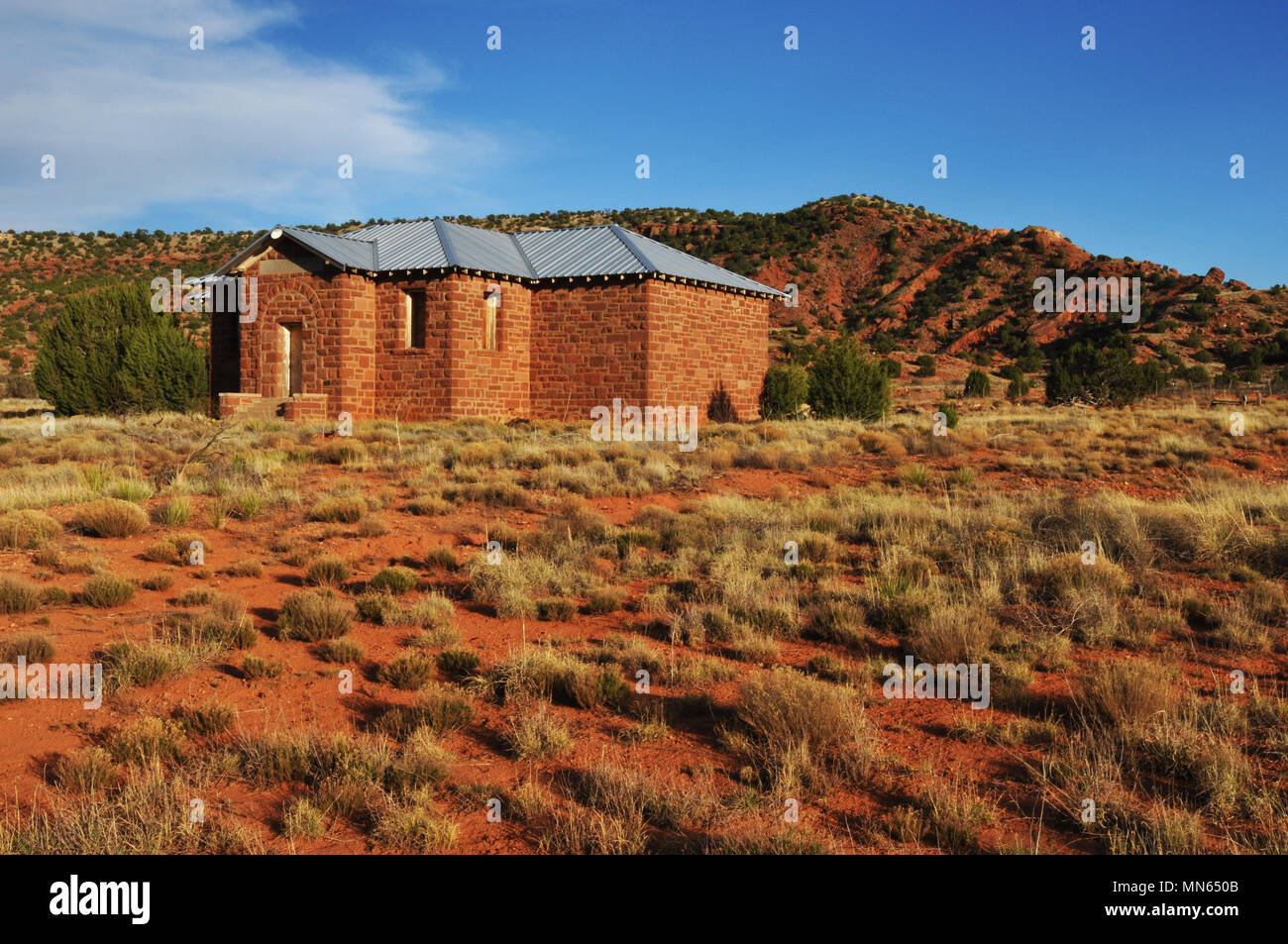 An old stone schoolhouse stands against a colorful landscape in the Route 66 town of Cuervo, New Mexico. Stock Photo
