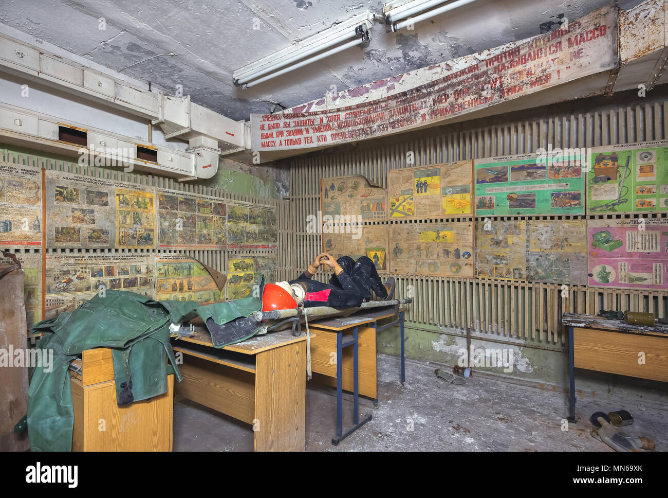 Room in an abandoned air-raid shelter during the Cold War with the Soviet slogan under the ceiling. Training class on civil defense with old desks, po Stock Photo