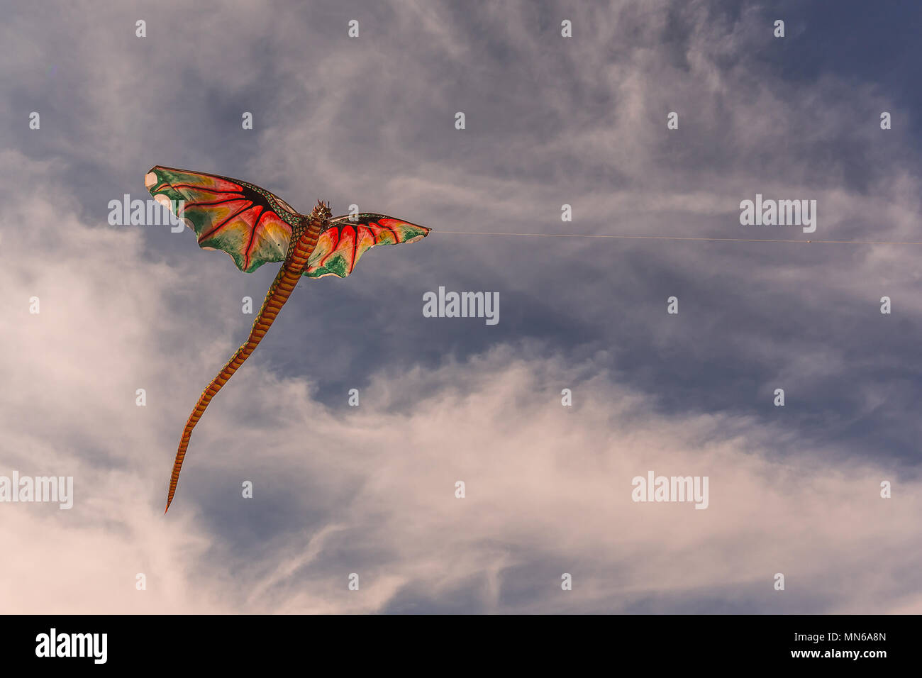 A red chinese kite with dragon head flying in the wind, Bali, Indonesia, april 21, 2018 Stock Photo