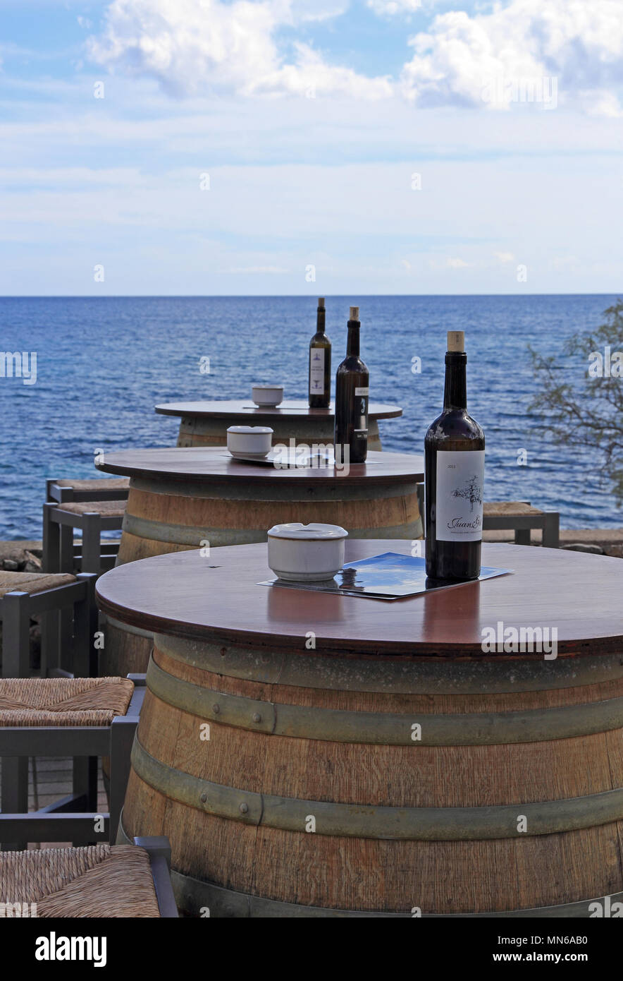 Barrels support table top with ashtrays and wine bottles outside seafront bar, Cala Bona, Mallorca Stock Photo