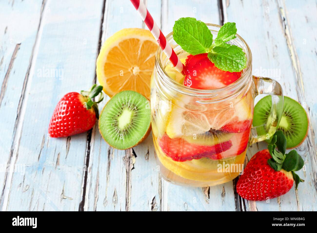 Lemon Strawberry Kiwi Detox Water In A Mason Jar Glass With Scattered Fruit Against A Rustic Blue Wood Background Stock Photo Alamy