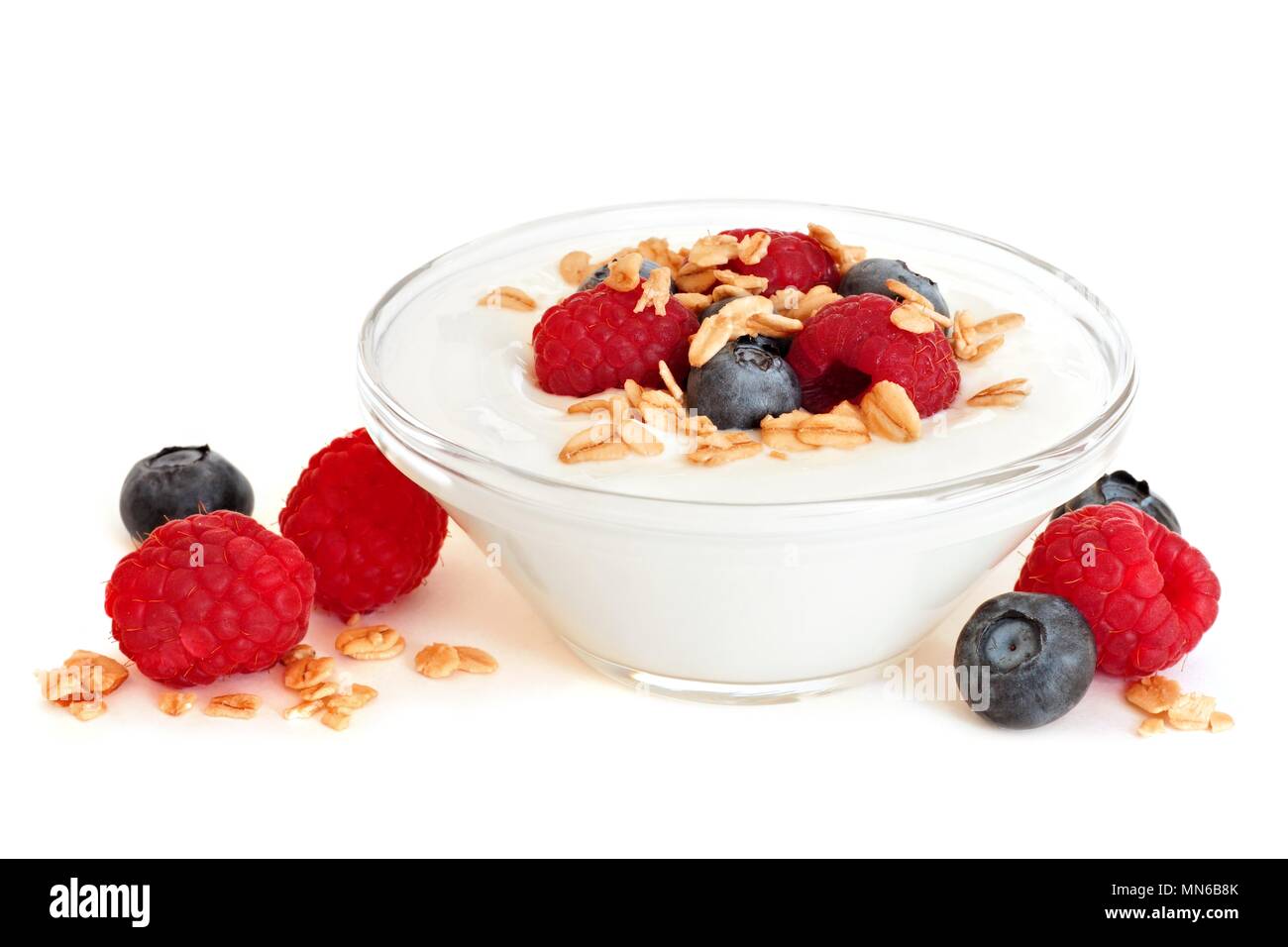 Clear bowl of yogurt with raspberries and blueberries over a white background Stock Photo
