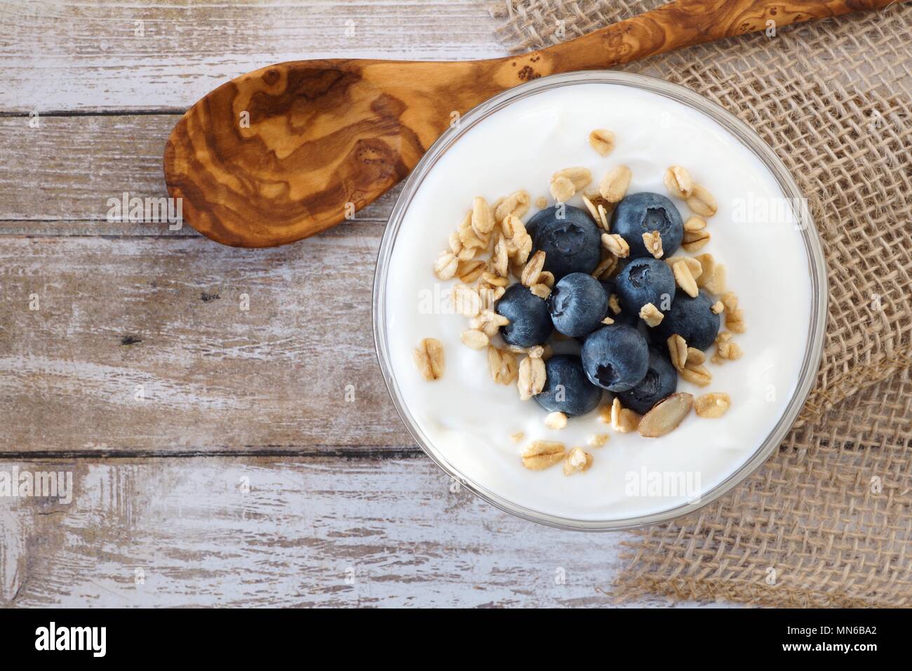 Yogurt with sweet blueberries and granola, above view on rustic wood Stock Photo