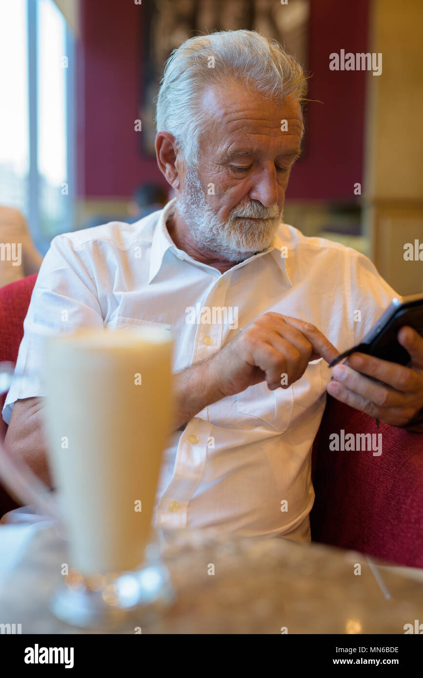 Handsome senior tourist man relaxing inside the coffee shop Stock Photo