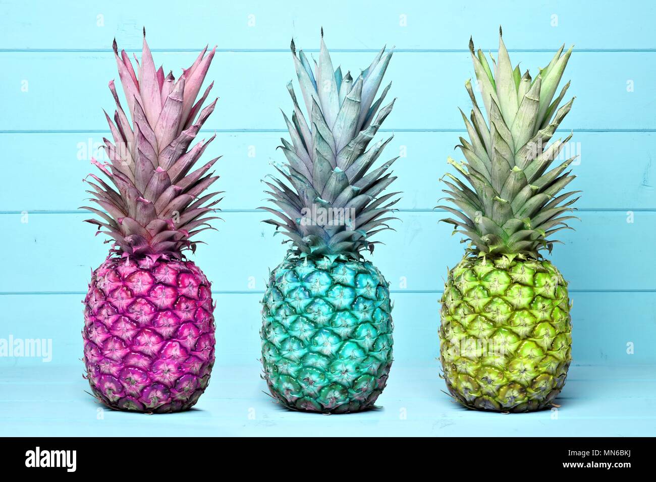 Pineapples of different color hues on a pastel blue wooden background