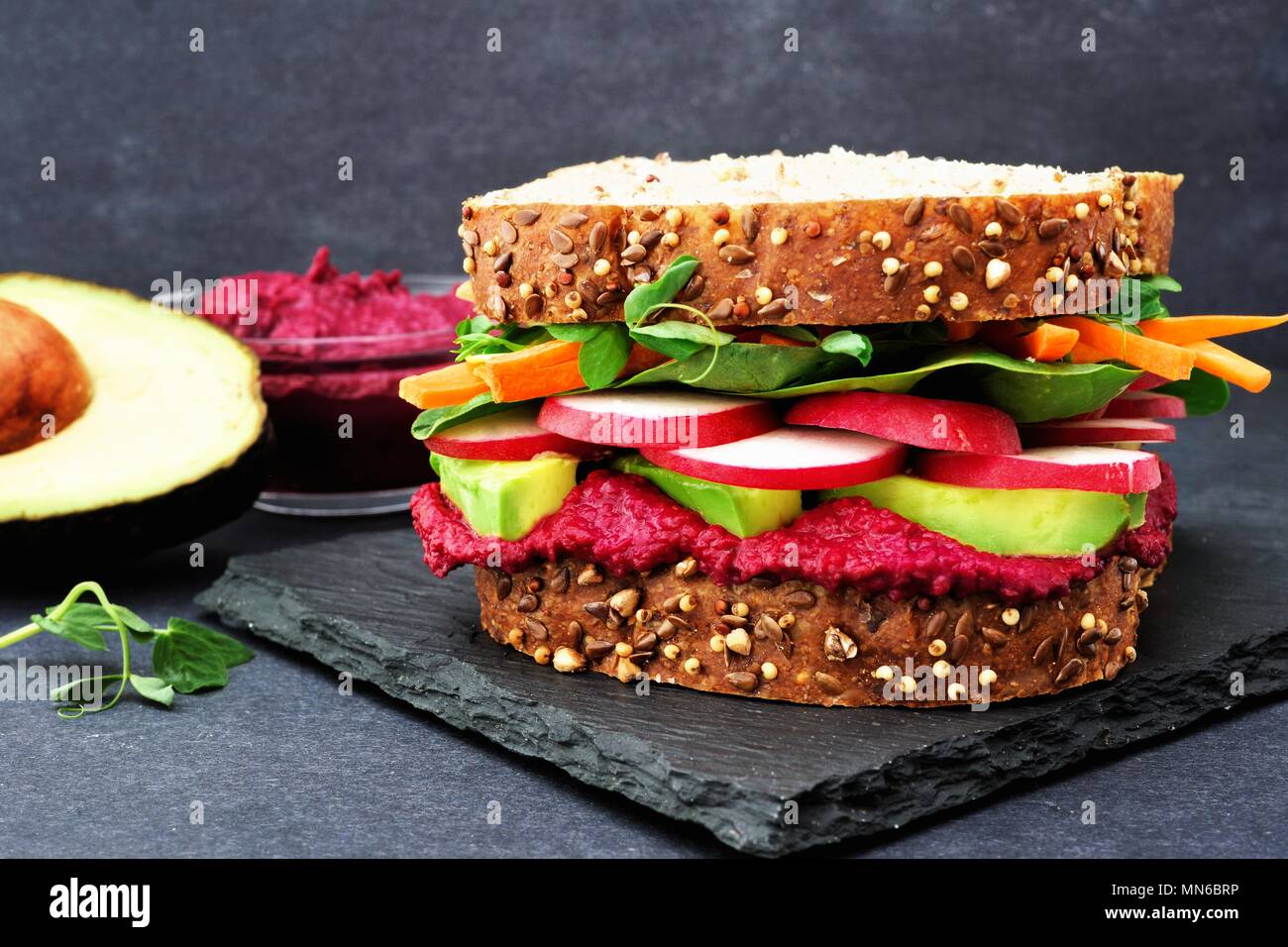 Superfood sandwich with beet hummus, avocado, vegetables and greens, on