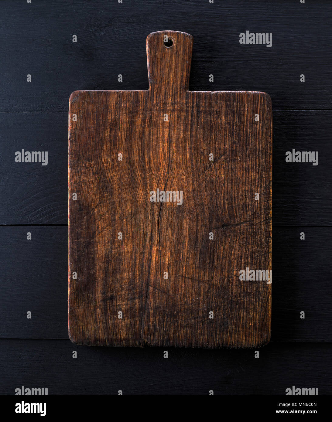 very old brown kitchen cutting board with handle, close up, black wood ...