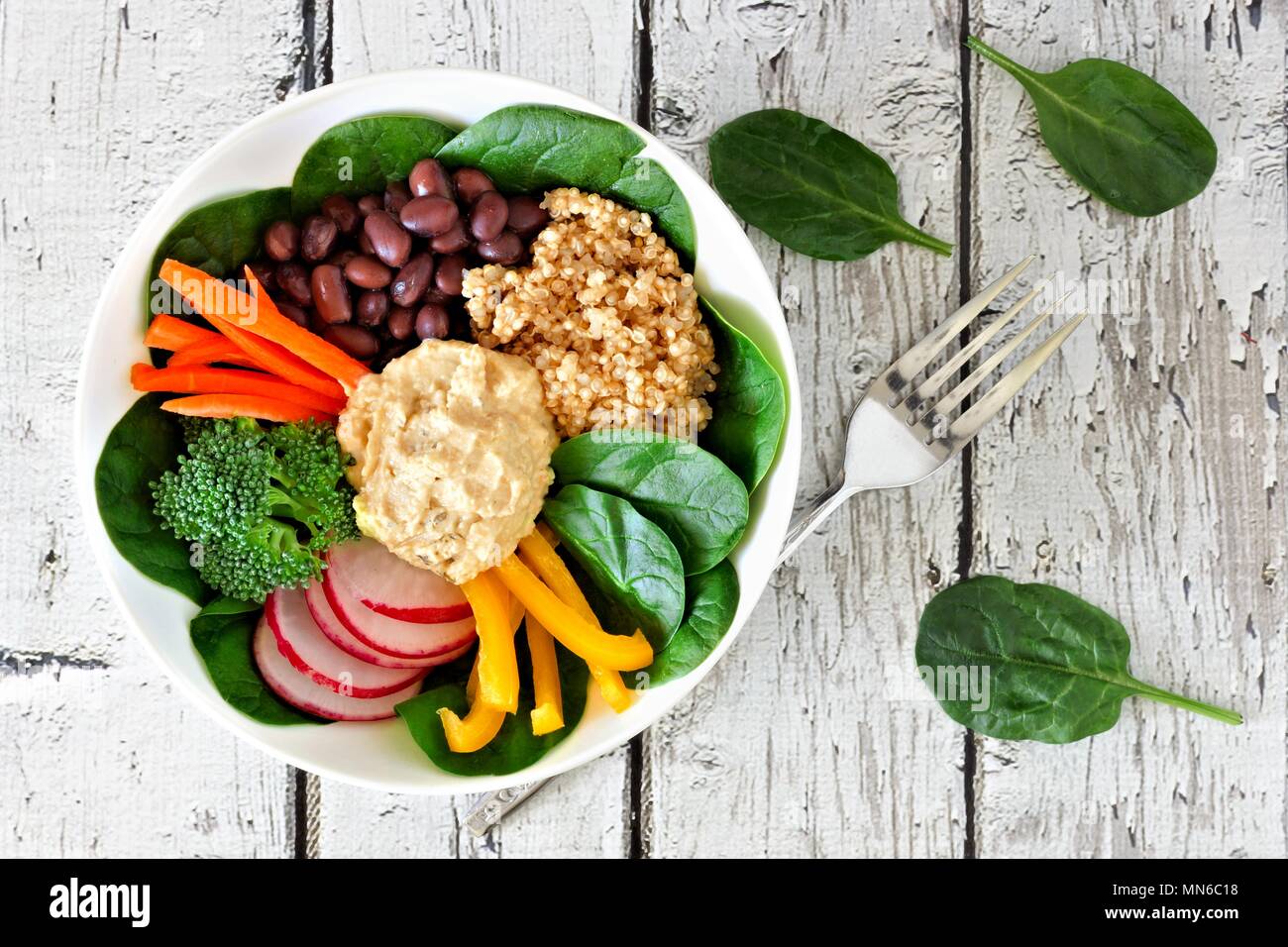 Healthy lunch bowl with quinoa, hummus and mixed vegetables, overhead scene on white wood Stock Photo