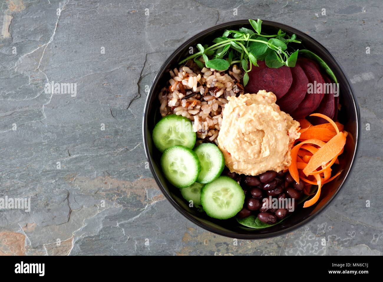 Healthy vegetarian salad bowl with hummus, beans, wild rice, beets