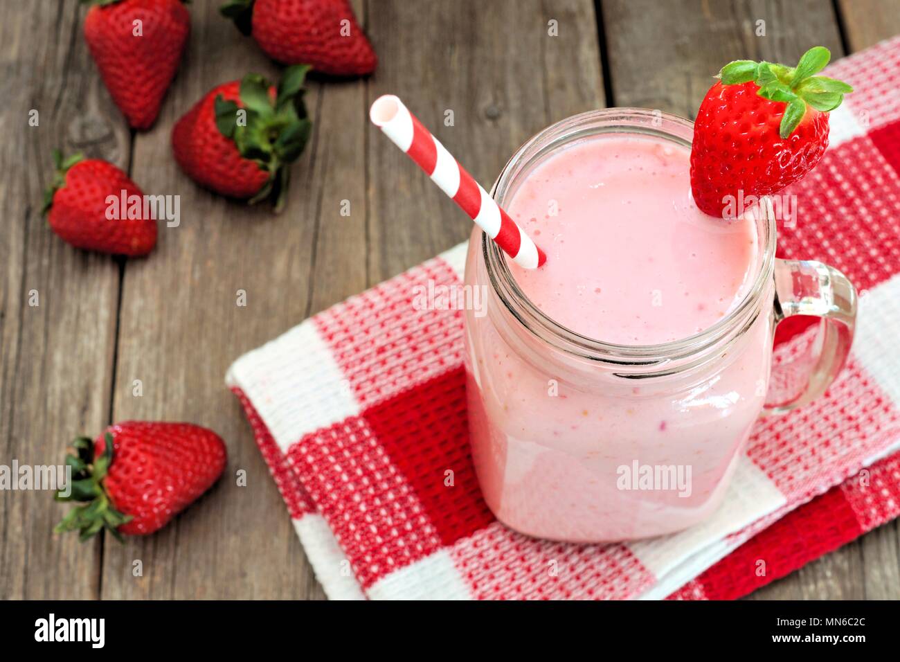 Healthy strawberry smoothie in mason a jar mug with checkered cloth against rustic wood Stock Photo