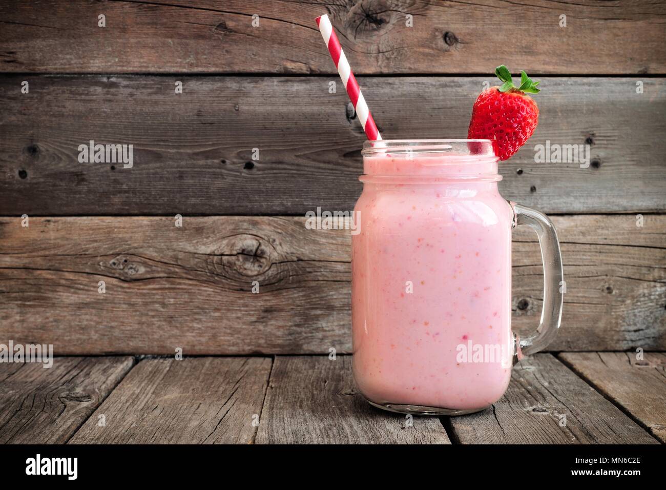 Healthy strawberry smoothie in a mason a jar mug over a rustic wood background Stock Photo
