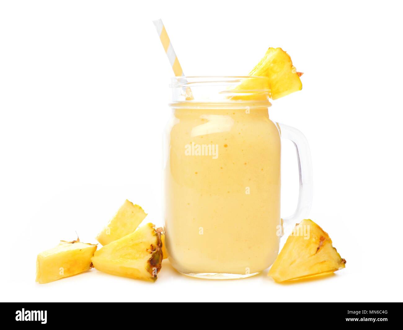 Pineapple smoothie in a mason jar with straw and scattered fruit isolated on a white background Stock Photo