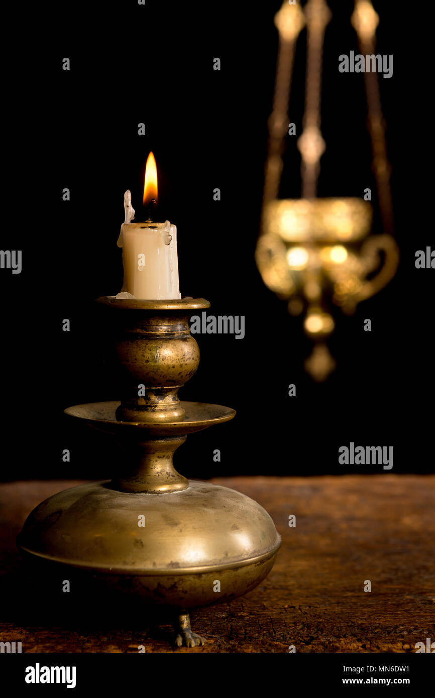 Antique candlestick and burning candle and in the background a blurred ...
