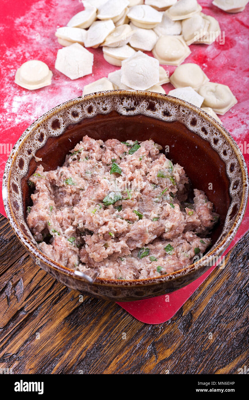 raw homemade dumplings with minced pork on the red surface. Stock Photo