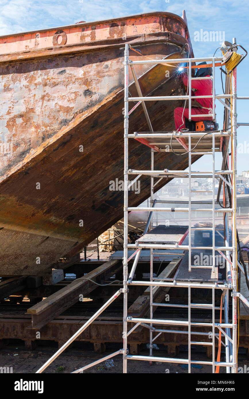 Workman welding on a rusty ship in the docks at Ramsgate Harbour, Kent