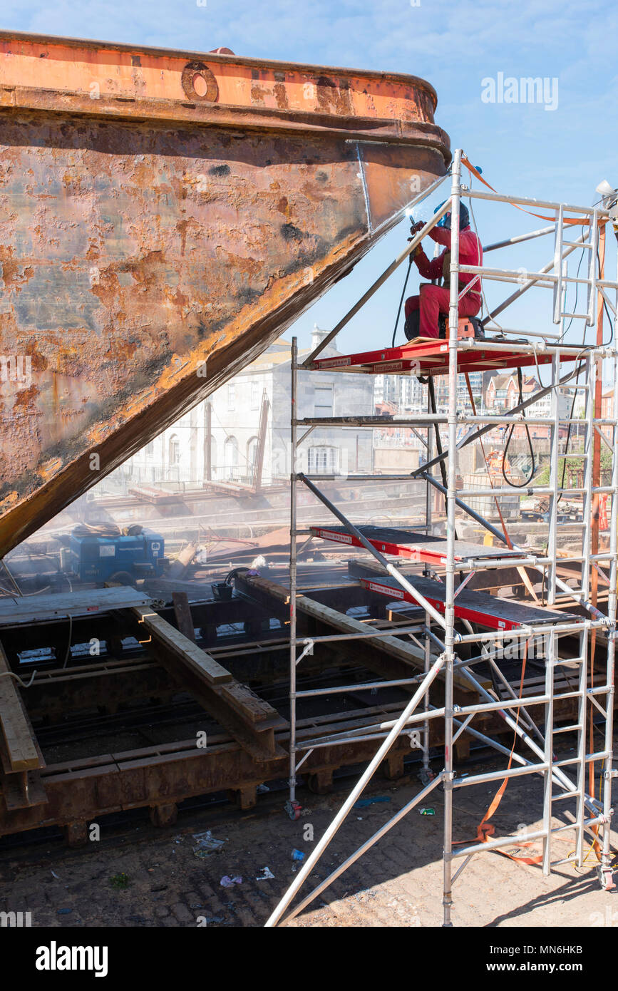Workman welding on a rusty ship in the docks at Ramsgate Harbour, Kent