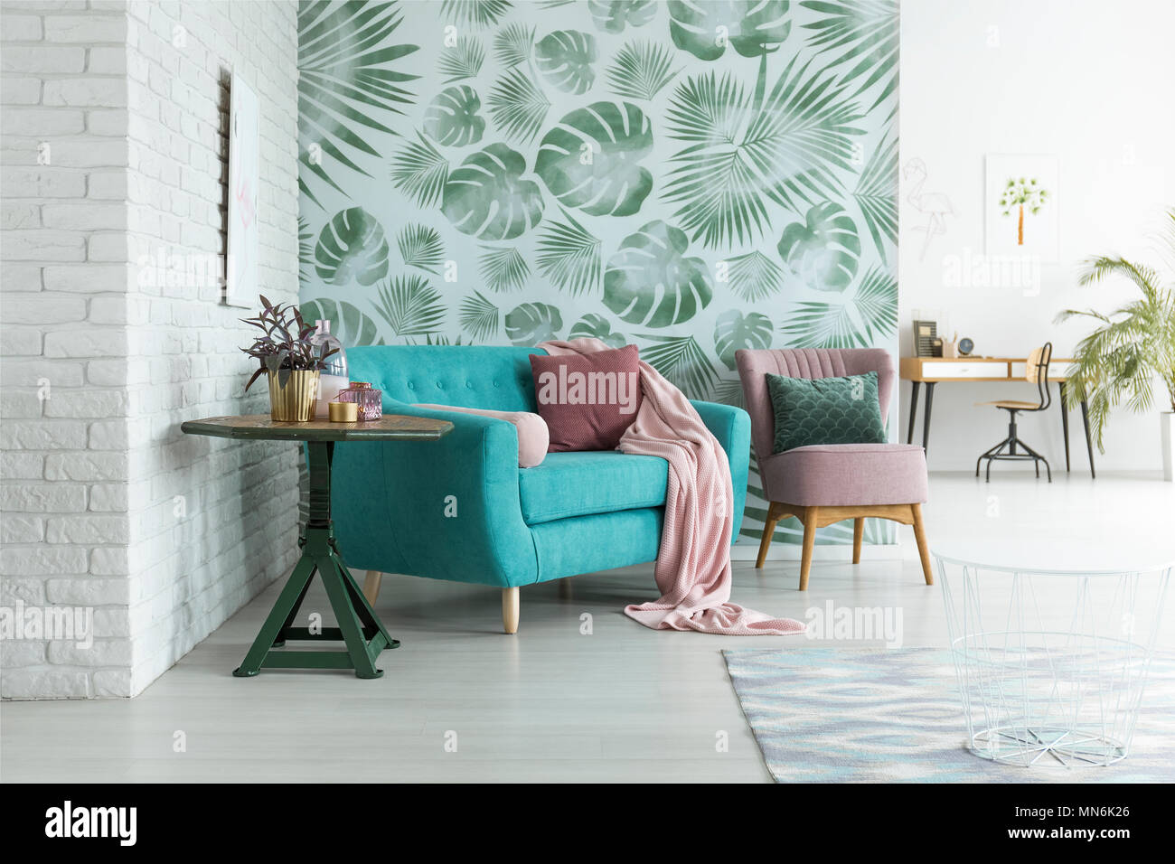 Green table with plant next to blue sofa and pink armchair with pillow