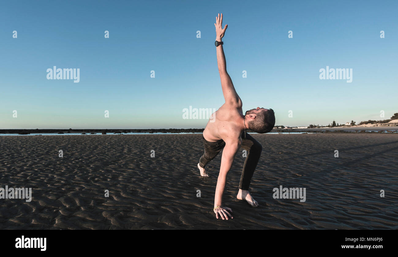 Young man doing yoga on the sand beach of Sanlucar de Barrameda when the tide is low Stock Photo