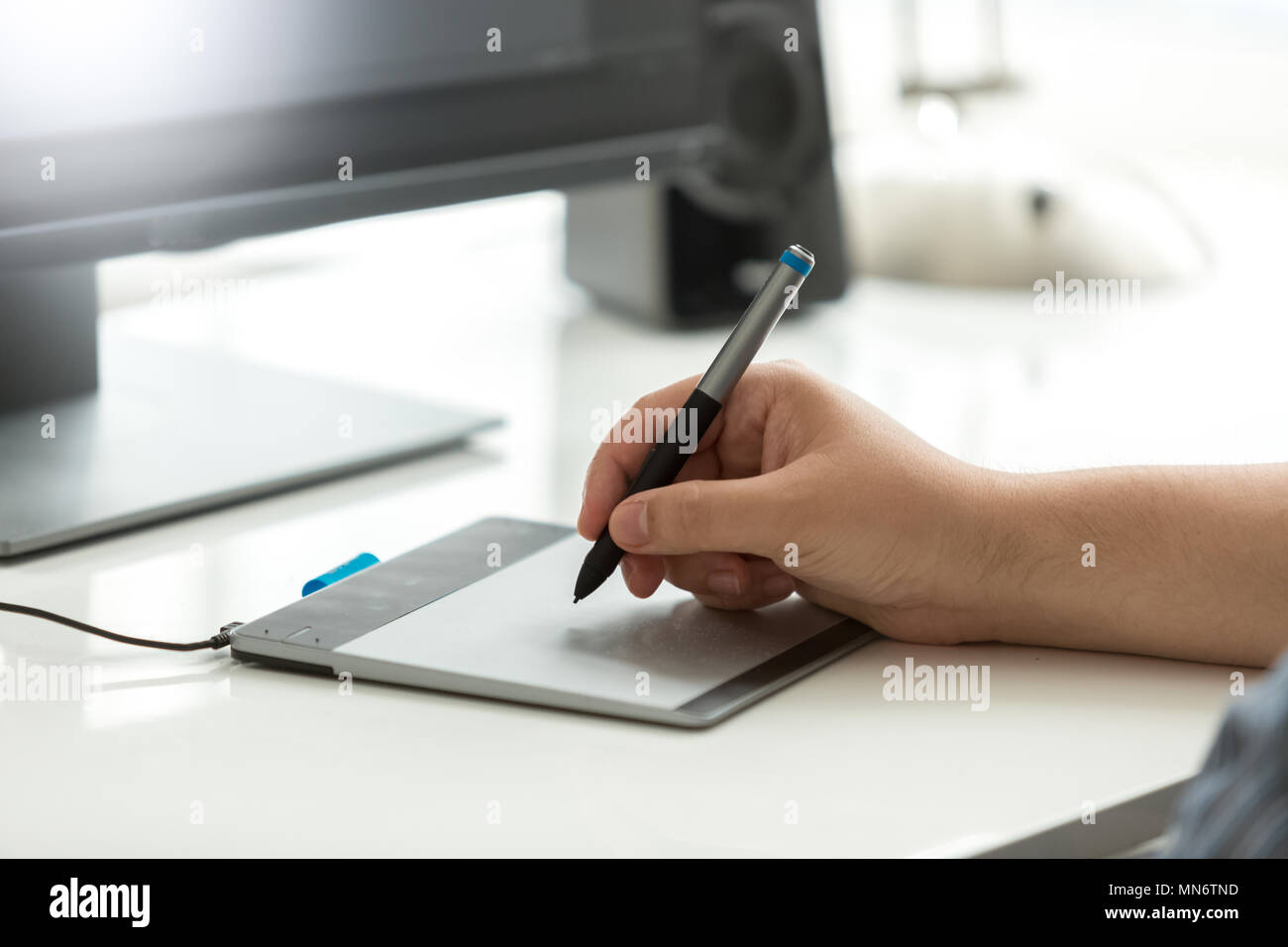 Closeup image of male hand holding stylus drawing sketches on graphic