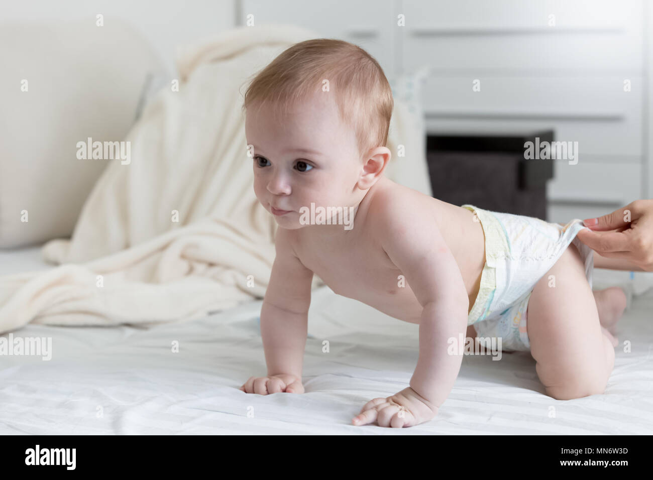 Cute 9 months old baby boy in diapers crawling on bed Stock Photo Alamy