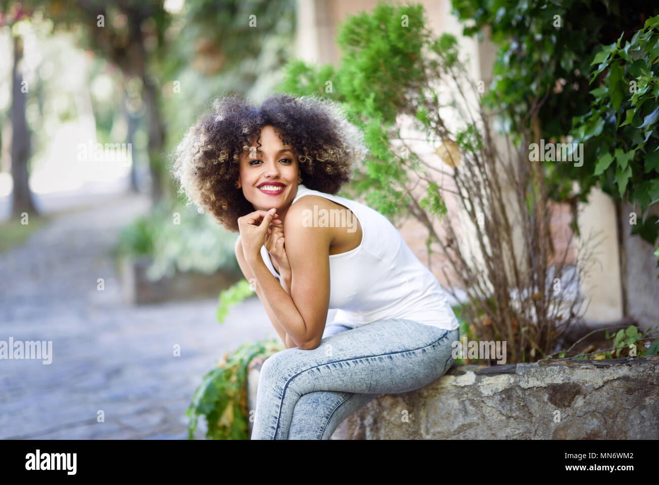 Young black woman with afro hairstyle smiling in urban park. Mixed girl ...