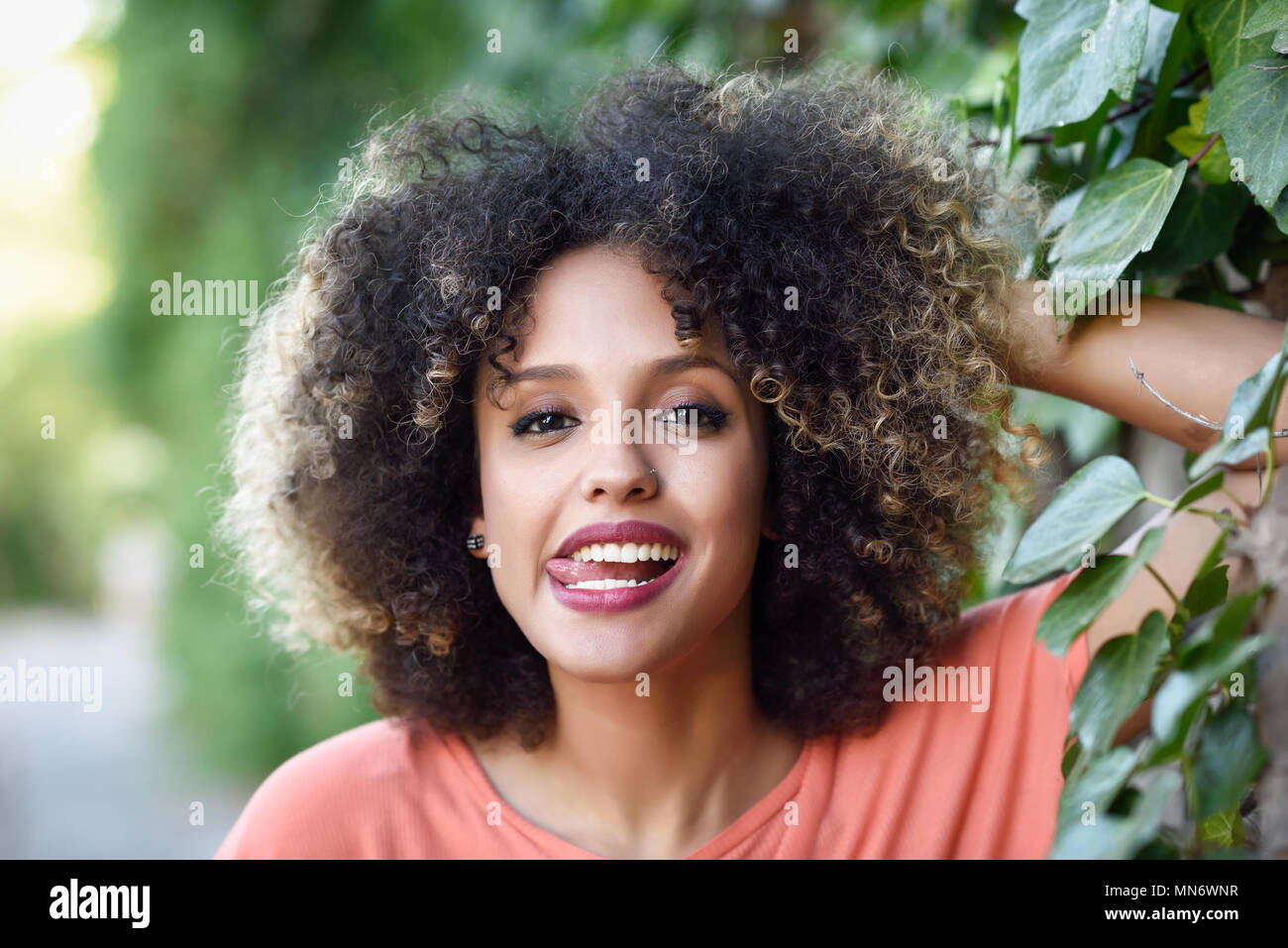 Black woman with tongue out in an urban park. Young mixed girl with