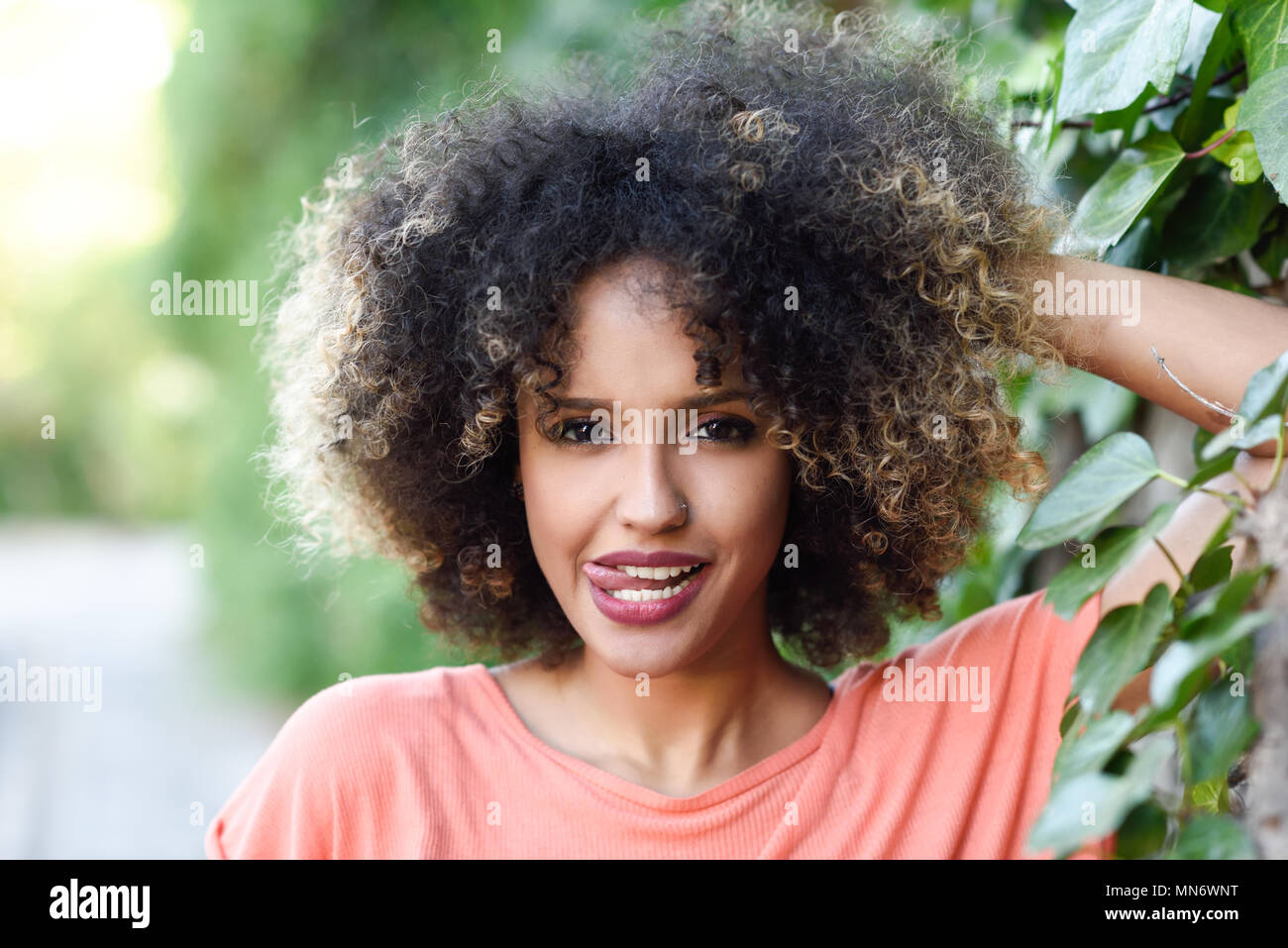 Black woman with tongue out in an urban park. Young mixed girl with