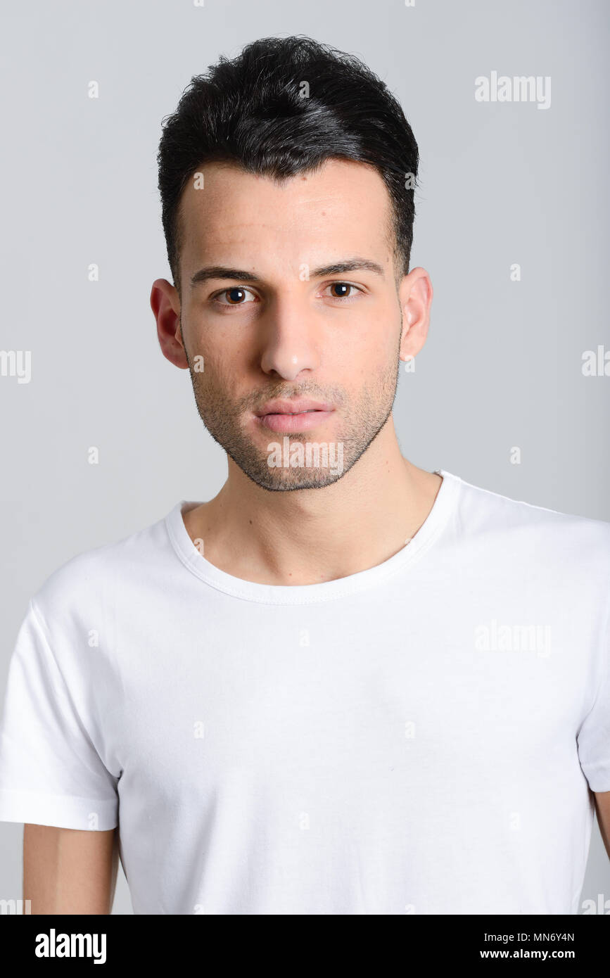 Portrait of a smart serious young man standing against white background ...