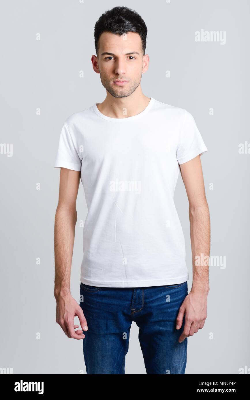 Portrait of a smart serious young man standing against white background ...