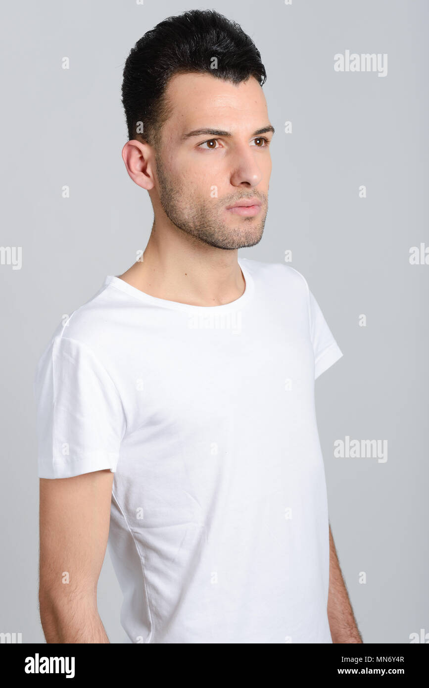 Portrait of a smart serious young man standing against white background ...