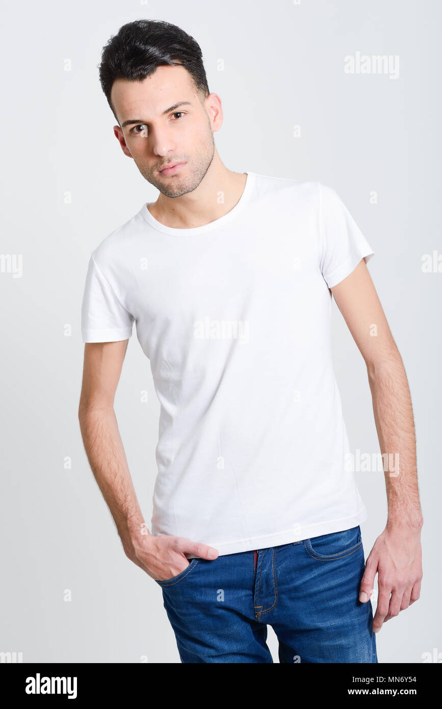 Portrait of a smart serious young man standing against white background ...
