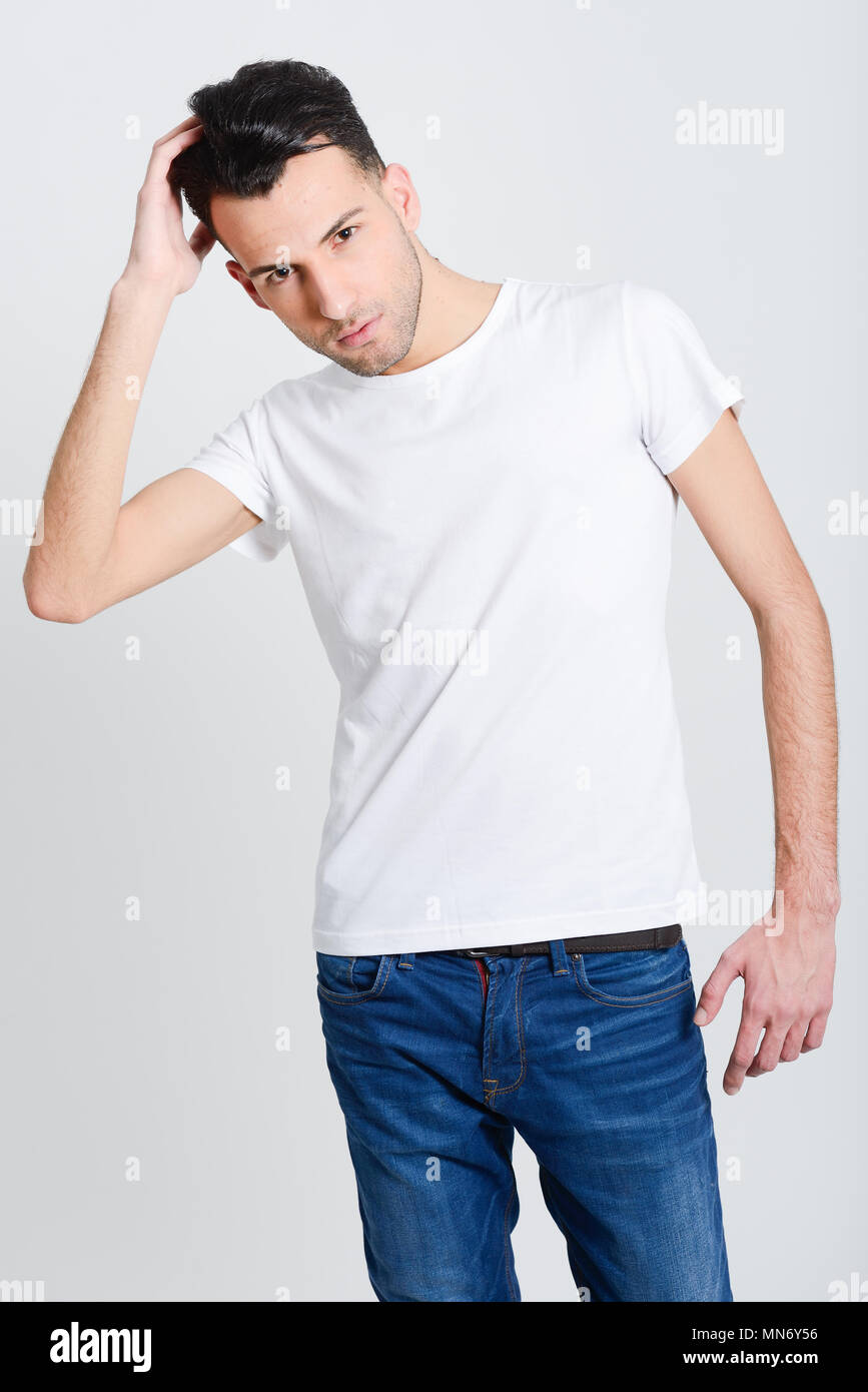 Portrait of a smart serious young man standing against white background ...