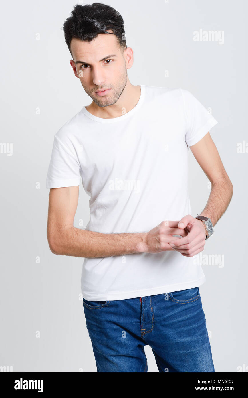 Portrait of a smart serious young man standing against white background ...