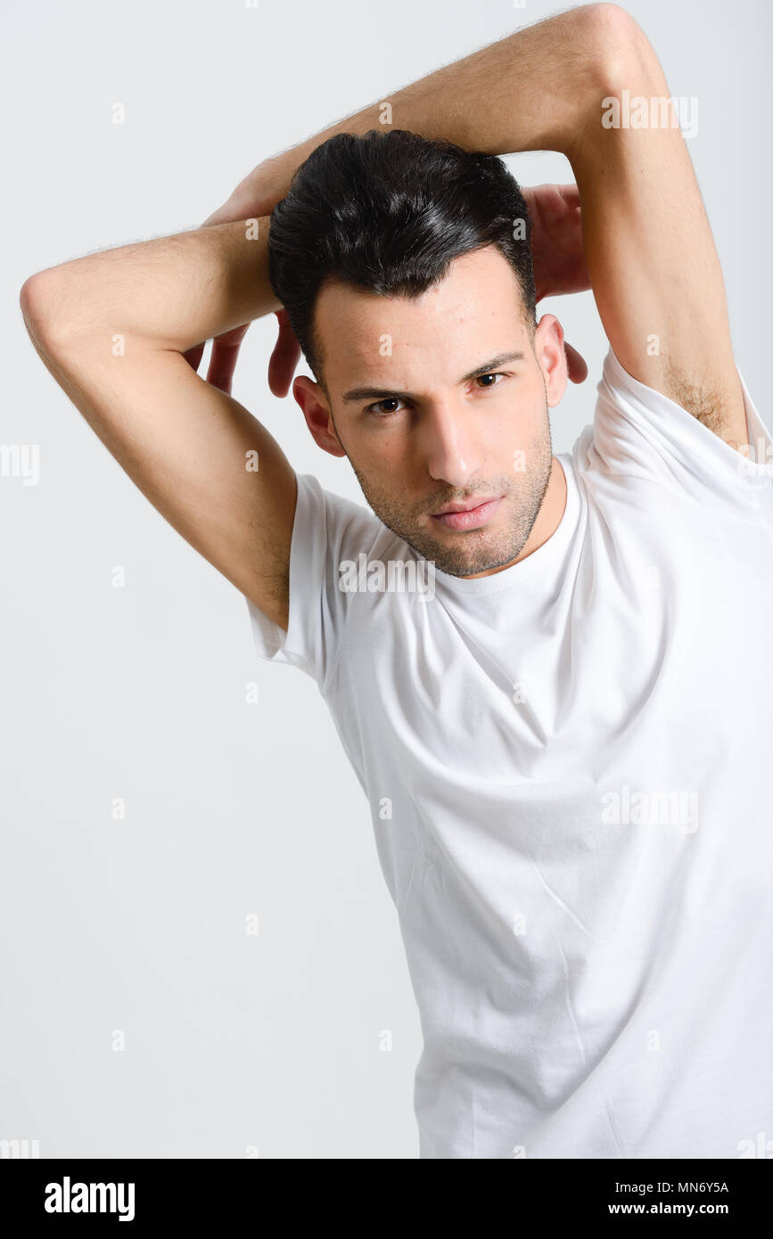 Portrait of a smart serious young man standing against white background ...