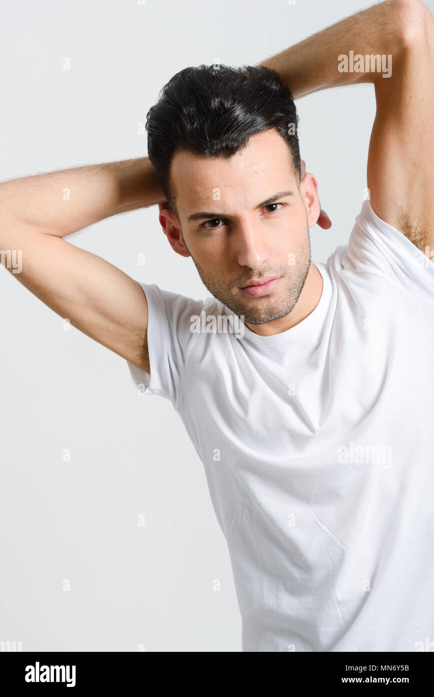 Portrait of a smart serious young man standing against white background ...