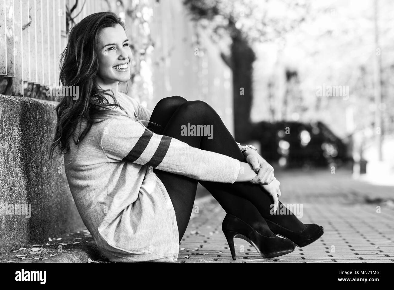 Portrait of funny female model of fashion with high heels sitting on