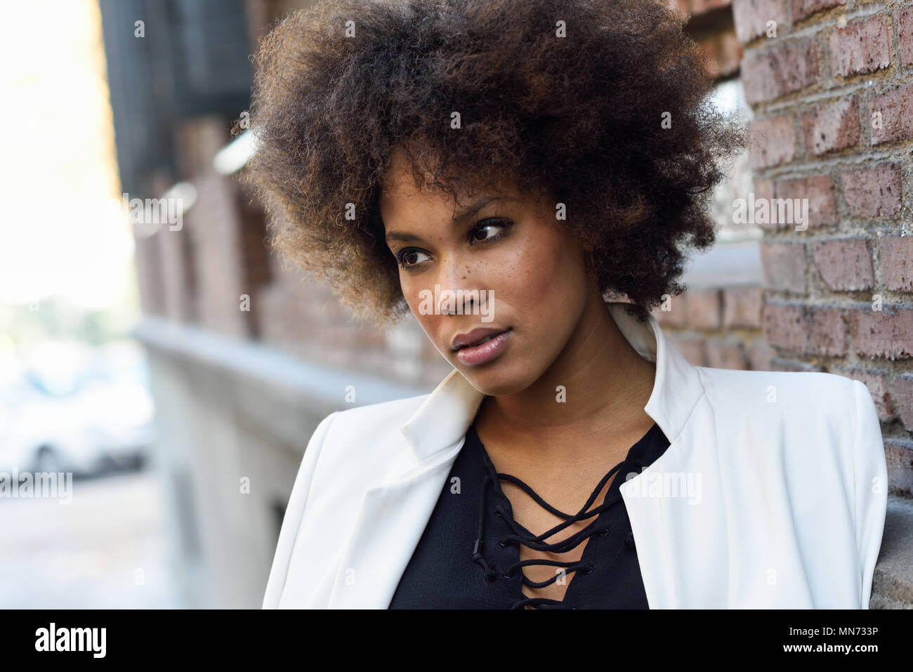 Young Black Woman With Afro Hairstyle Standing In Urban Background