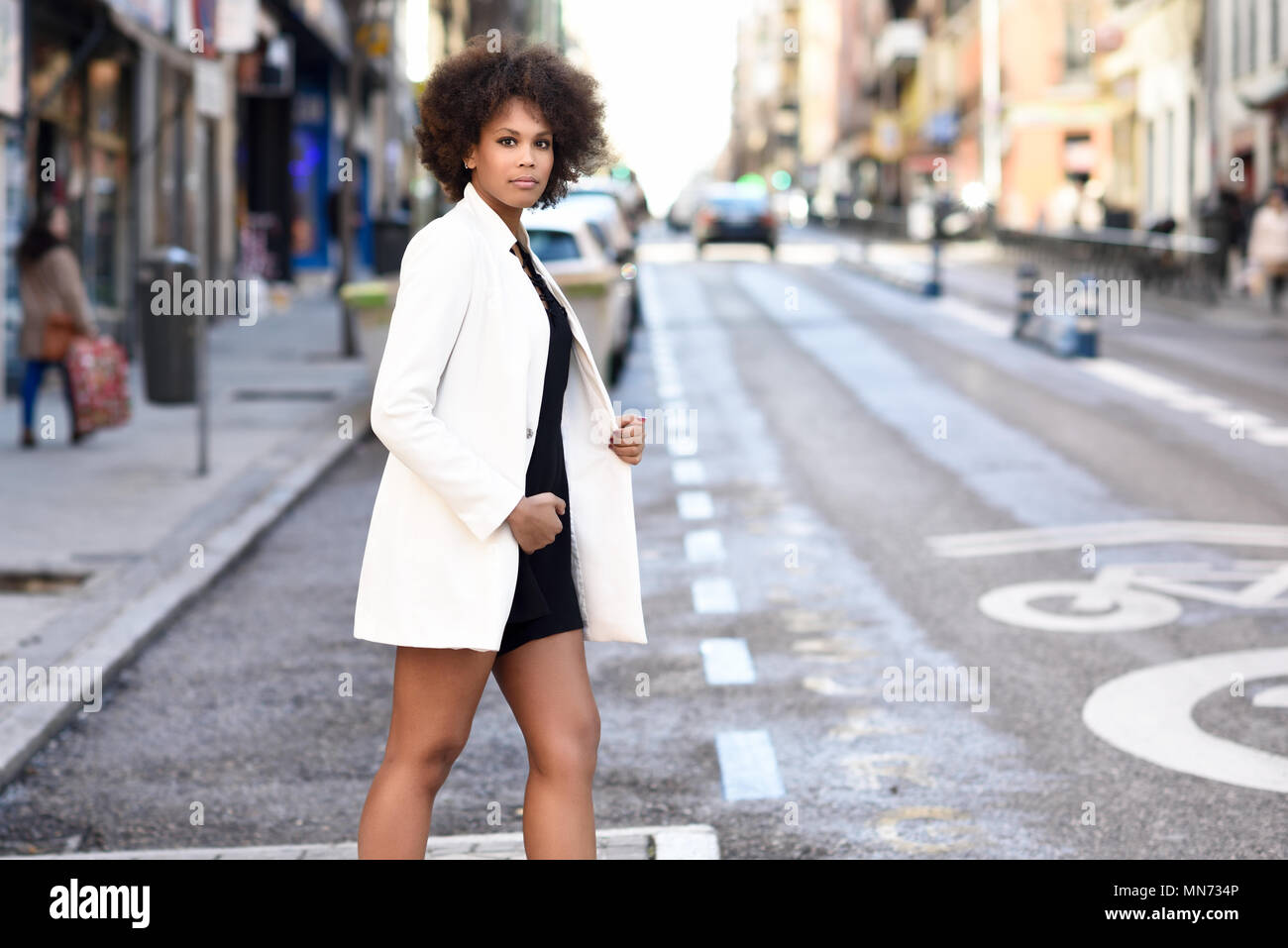 Young black woman with afro hairstyle walking on a crosswalk in an ...