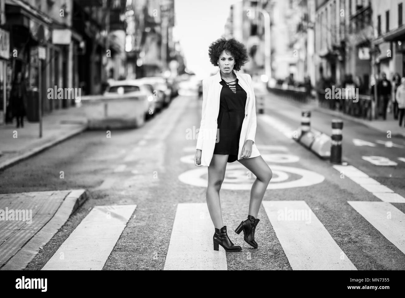 Young black woman with afro hairstyle walking on a crosswalk in an ...