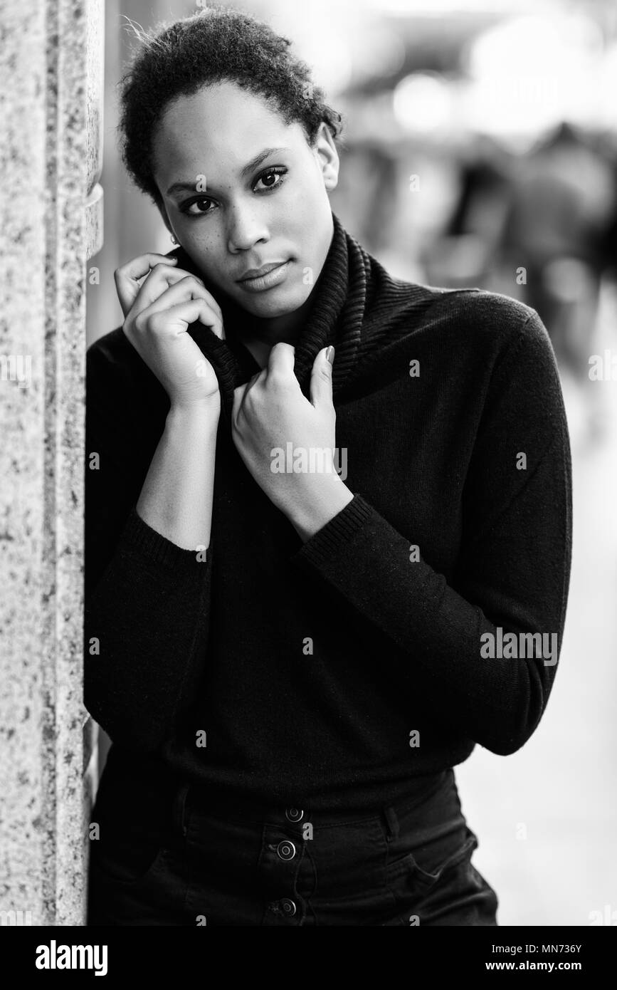 Young black female standing in an urban street. Mixed woman wearing poloneck sweater and skirt. Stock Photo