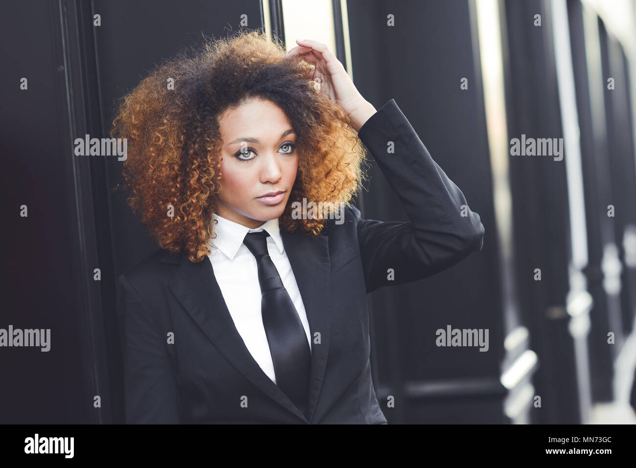 Portrait of beautiful black businesswoman wearing suit and tie in urban ...