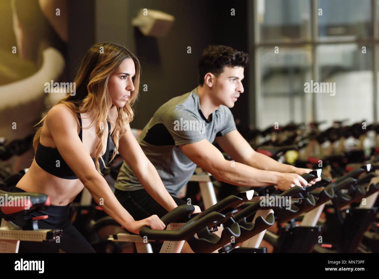 Couple training indoor cycling in a gym 