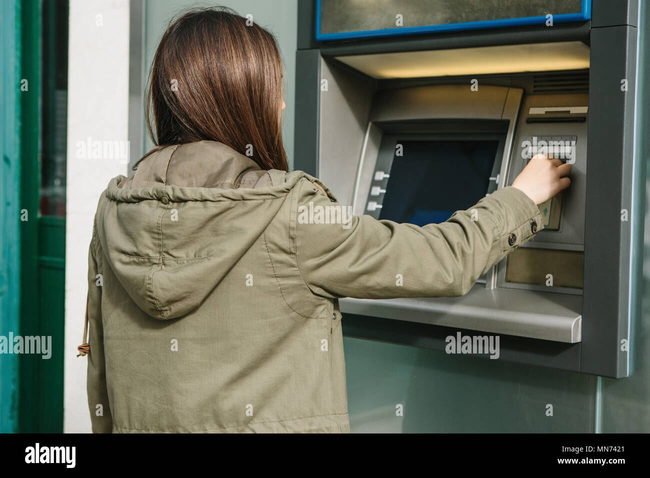 A young woman takes money from an ATM. Grabs a card from the ATM. Finance, credit card, withdrawal of money. Stock Photo