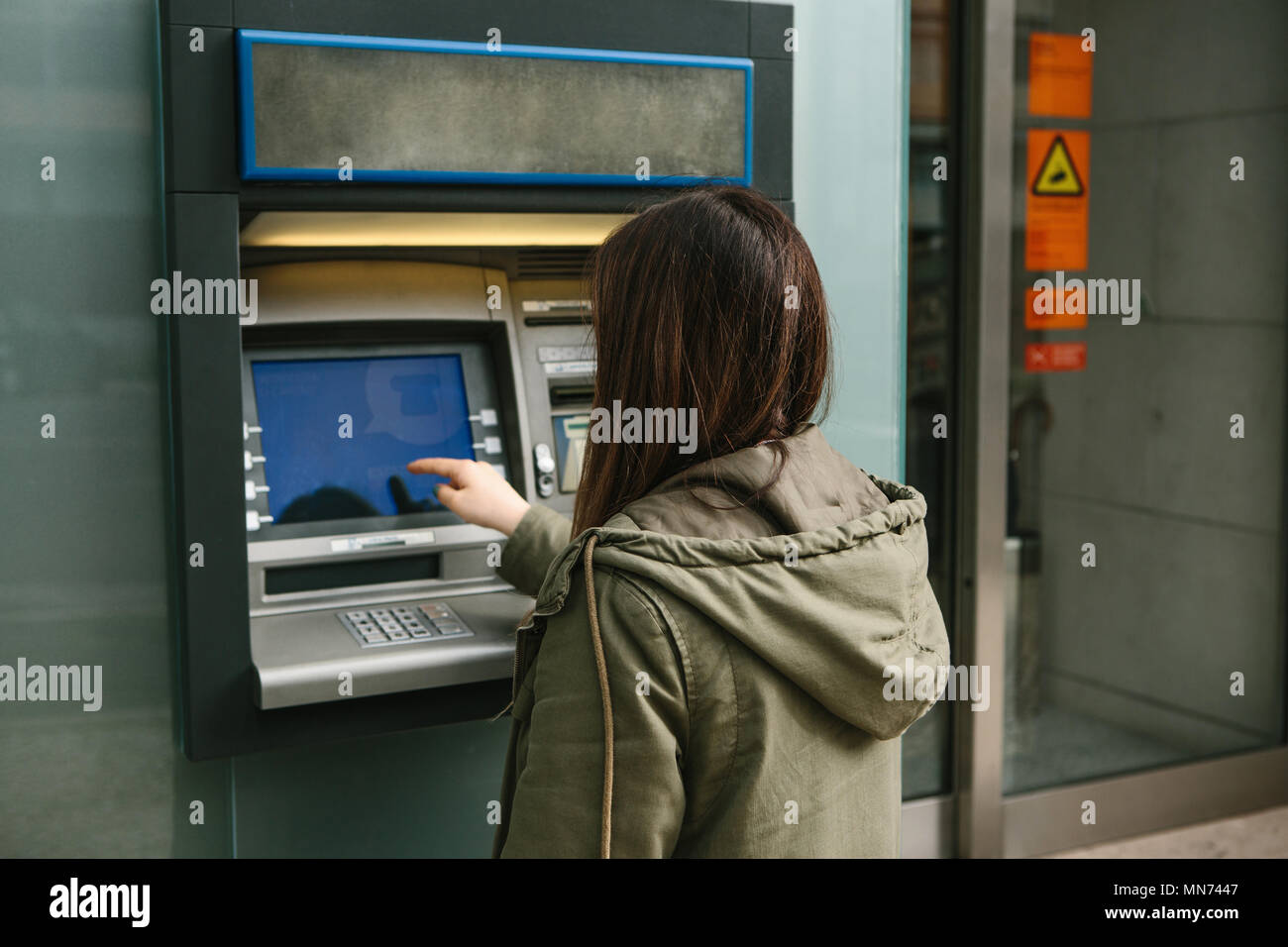A young woman takes money from an ATM. Grabs a card from the ATM. Finance, credit card, withdrawal of money. Stock Photo