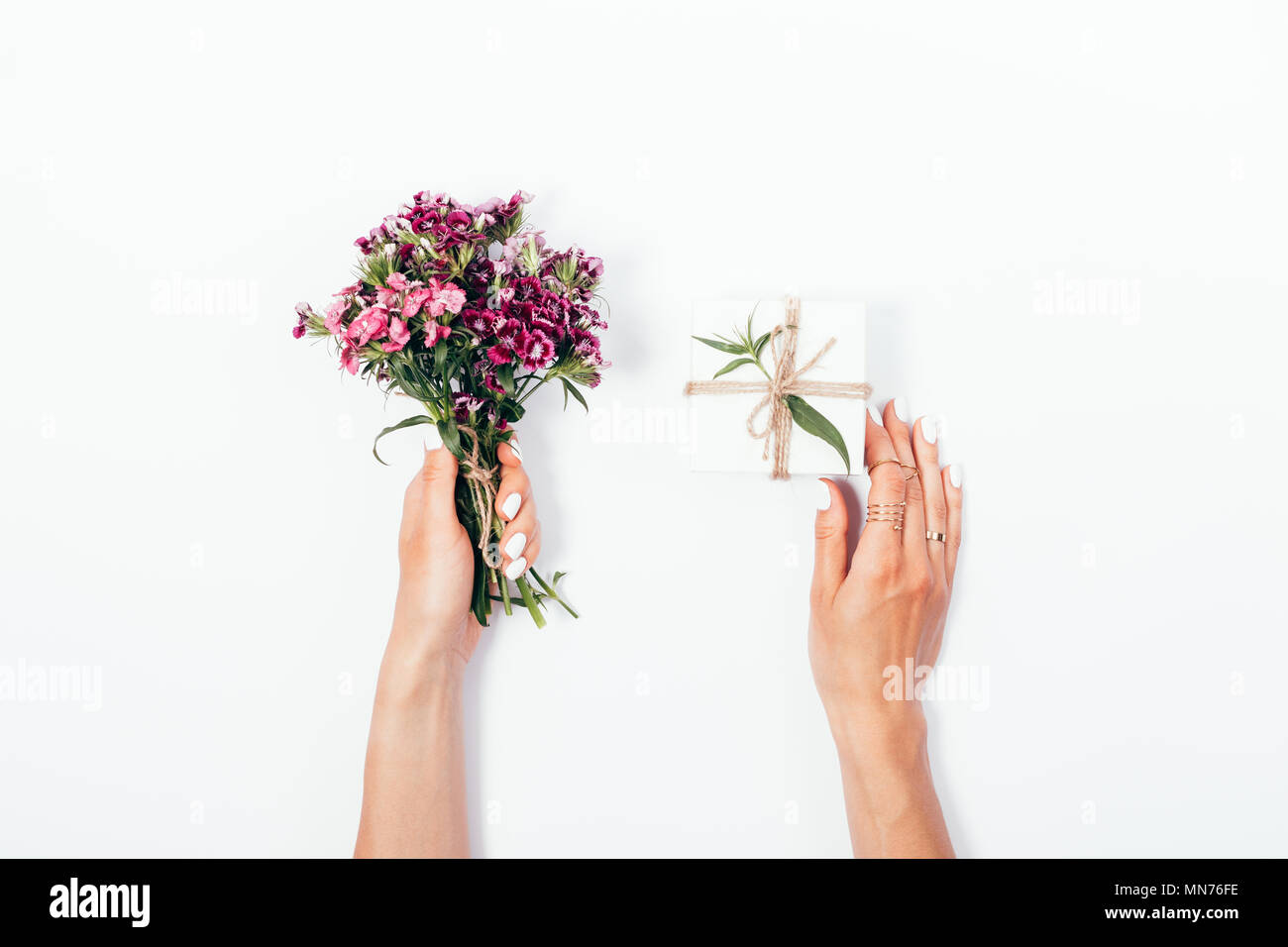 Woman's hands holding small bouquet and tiny gift box tied with jute ...