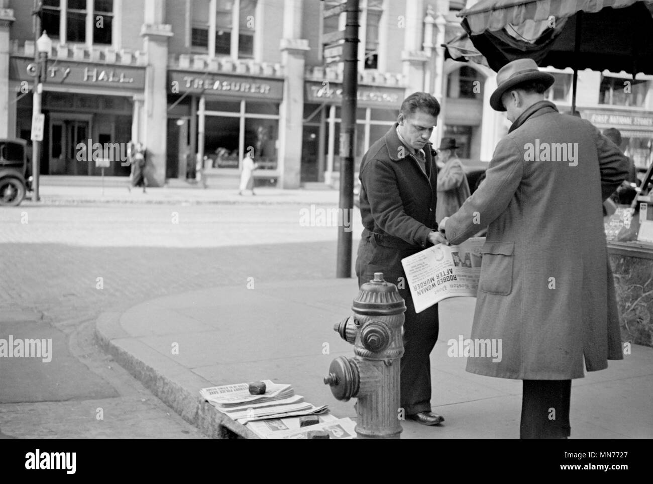 Man Selling Newspapers on Street Corner, Manchester, New Hampshire, USA, Carl Mydans for U.S. Resettlement Administration, August 1936 Stock Photo